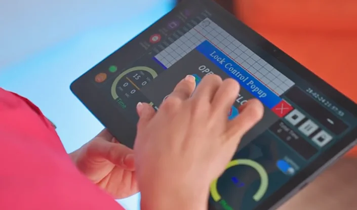 A person uses a tablet displaying the Apex HBOT's control interface with buttons and graphs, including a Lock Control Popup window and various circular gauges.