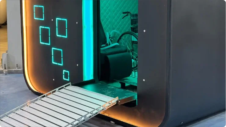 A modern black Matrix hyperbaric oxygen therapy (HBOT) chamber with glowing blue lights, a metal ramp, and an open entrance that reveals a bicycle and a mat inside.